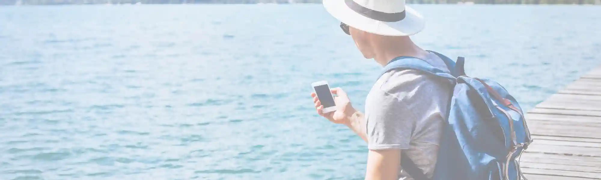 Online Business zum Auswandern- Mann mit Handy am Meer